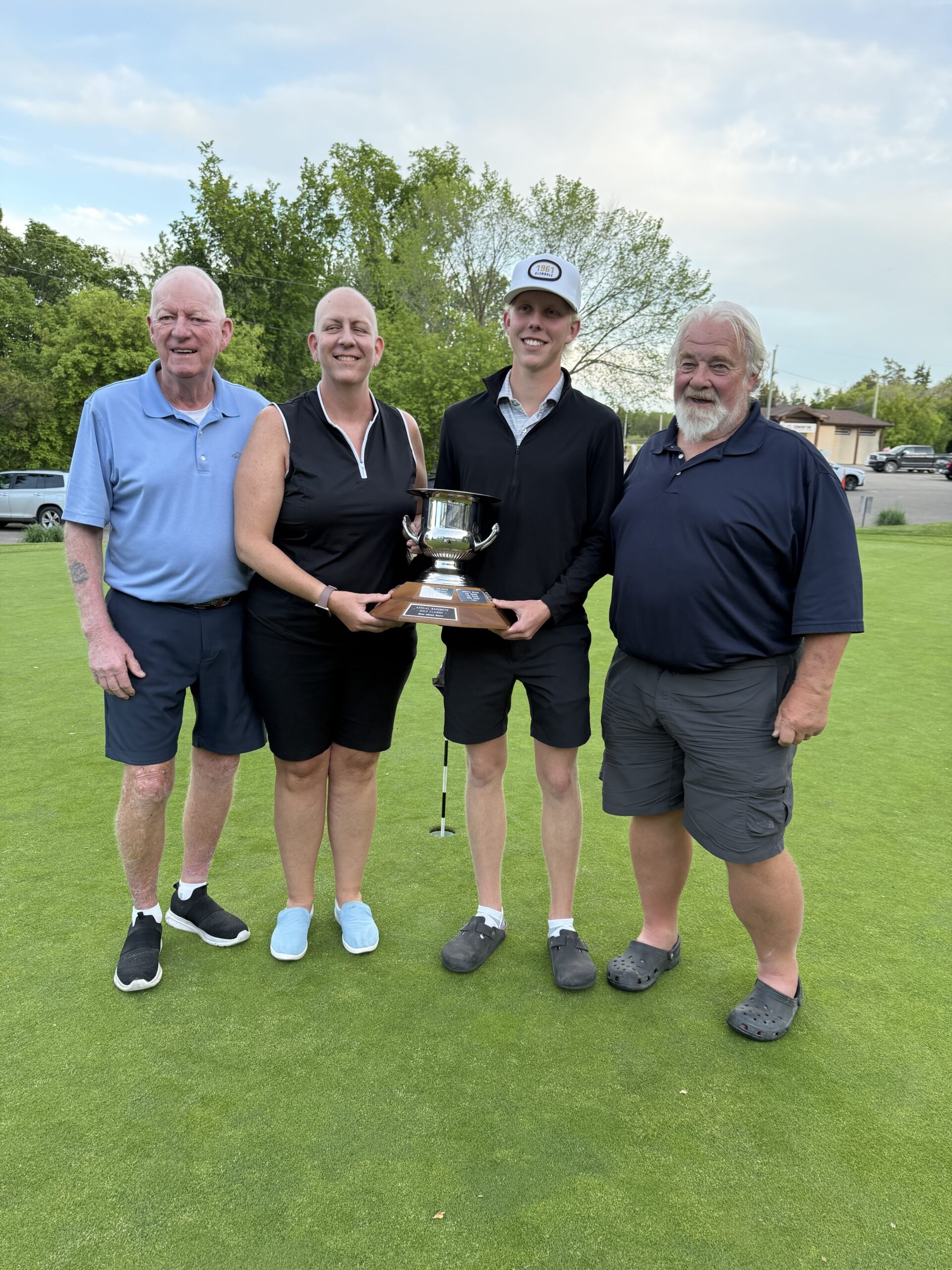 Golf team holding trophy on green